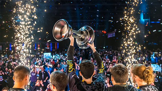 Person holding the Halo World Championship trophy in front of a cheering crowd.