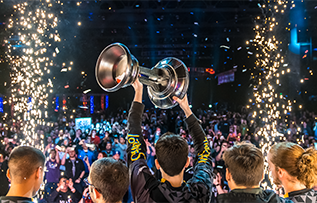 Person holding the Halo World Championship trophy in front of a cheering crowd.